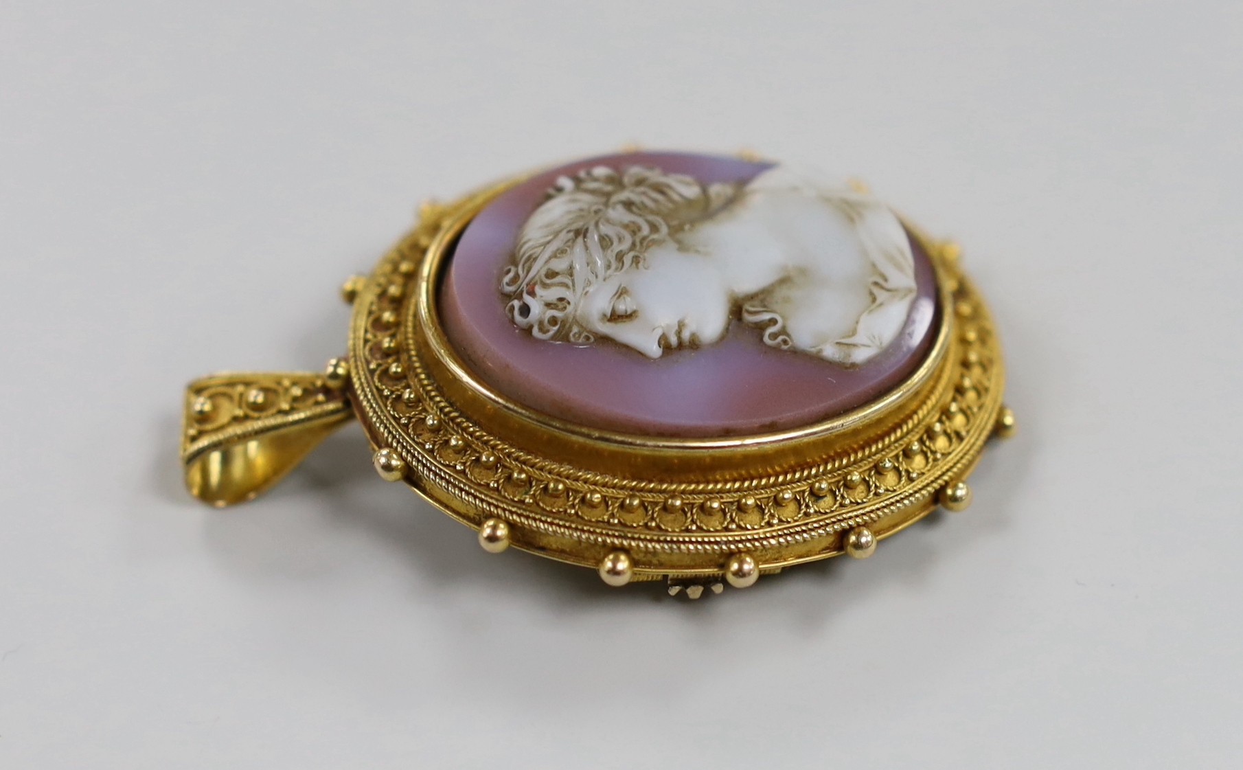 A Victorian yellow metal and hardstone cameo set oval pendant brooch (pin missing) with cannetile work decoration and engraved inscription verso, the stone carve with bust of a lady to dexter, overall 55mm, gross weight